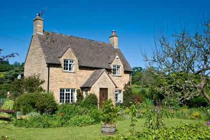 A picturesque detached cottage set in gardens with blue sky.A house with an interesting history 